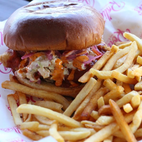 Rollies Mexican Patio's crispy chicken sandwich with coleslaw, sauce, and a side of fries.