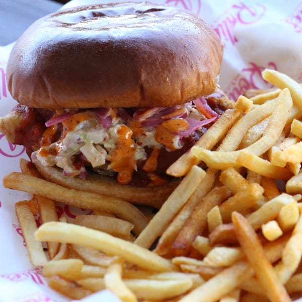 Rollies Mexican Patio's fried chicken sandwich with slaw, sauce, and a side of fries.