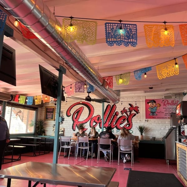 Rollies Mexican Patio interior with colorful papel picado, red floor, and diners at tables.