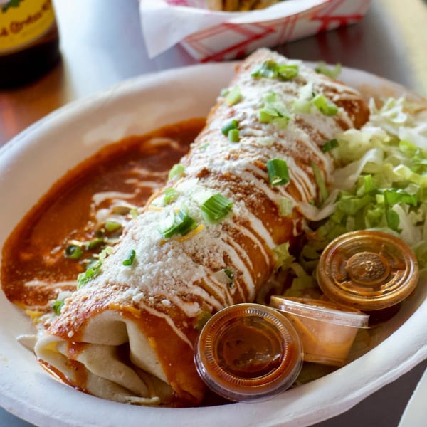 Rollies Mexican Patio's burrito covered in red sauce, cheese, sour cream, and green onions.