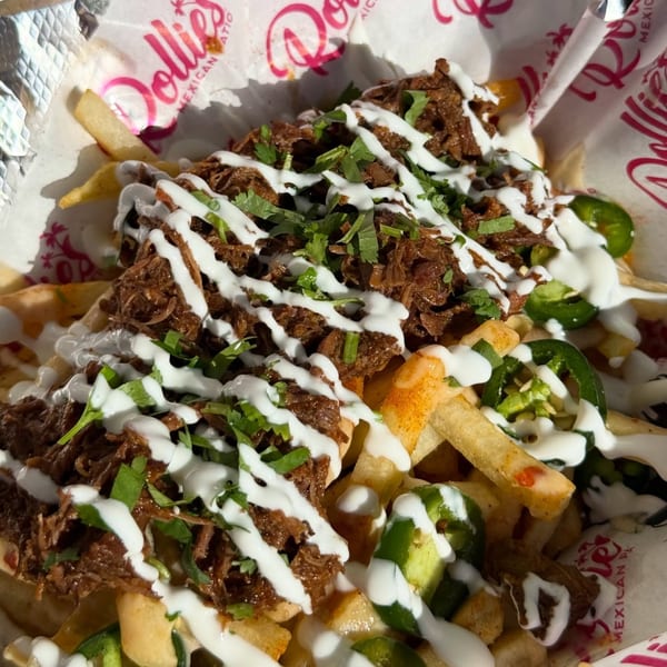 Close-up of Rollies Mexican Patio's carne asada fries with sour cream, cilantro, and jalapeños.