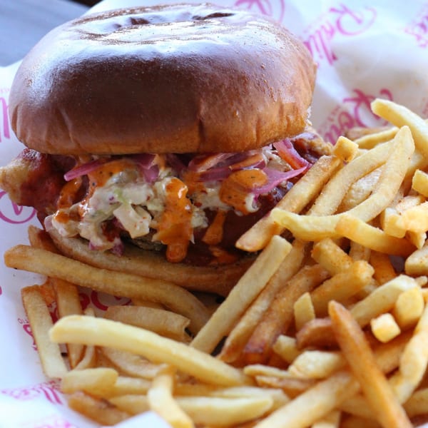 Rollies Mexican Patio's crispy chicken sandwich with slaw and sauce, served with golden fries.