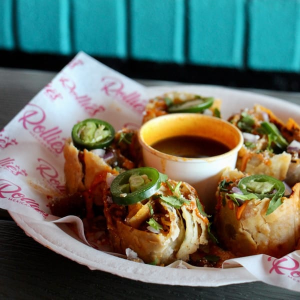 Rollies Mexican Patio's deep-fried tacos with jalapeños, cilantro, and a side of dipping sauce.