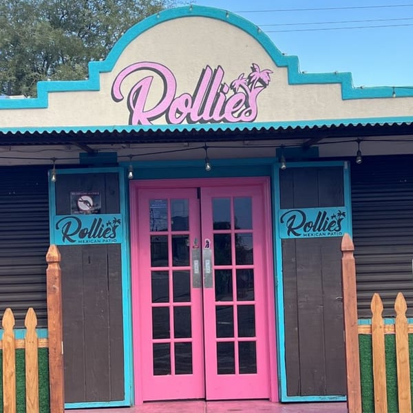 The vibrant pink and blue exterior of Rollies Mexican Patio, featuring a pink double door entrance.